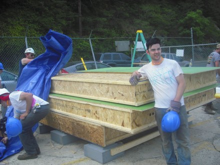 eric is leaning on wall panel, two students working on the side